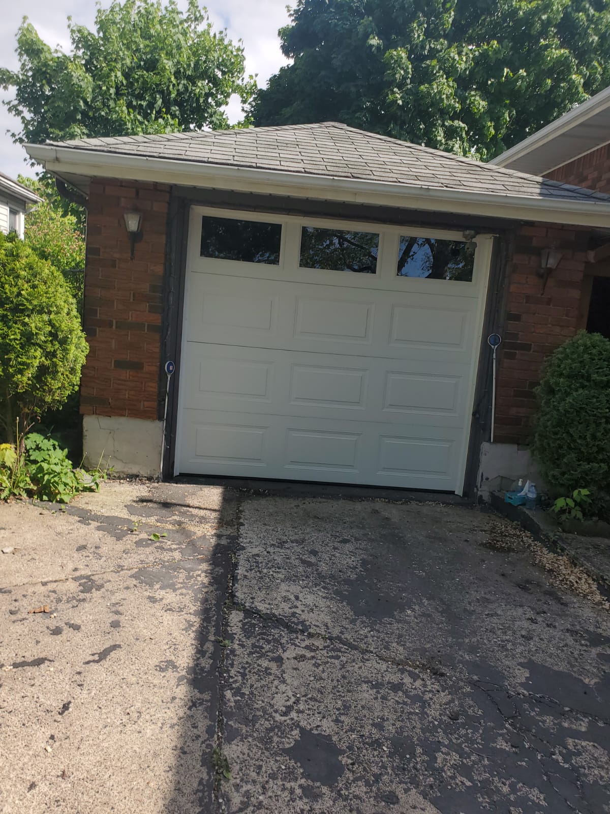 Completed white raised-panel garage door on a brick garage